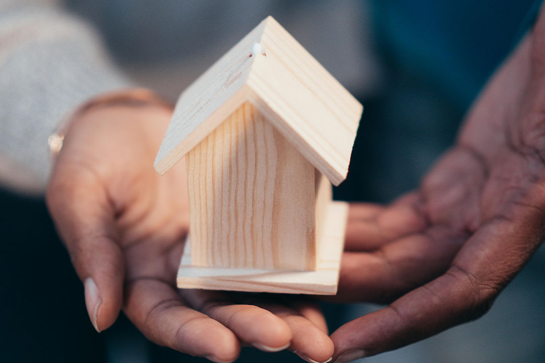 Persona sosteniendo una casa pequeña de madera